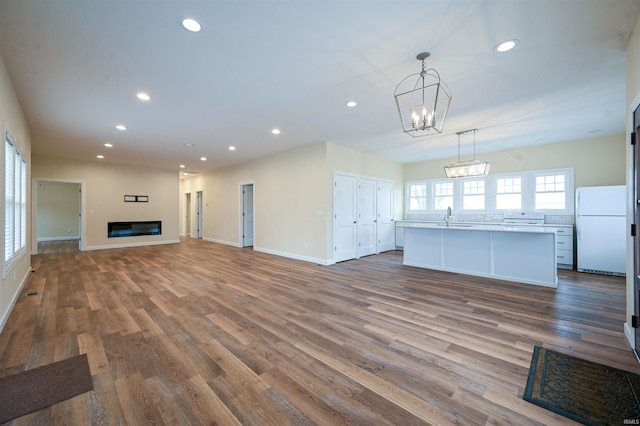 unfurnished living room featuring hardwood / wood-style flooring, sink, and an inviting chandelier