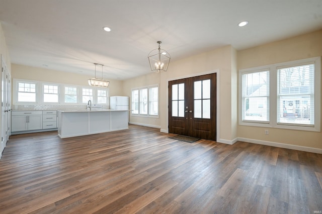 foyer entrance with sink, dark wood-type flooring, a notable chandelier, and french doors