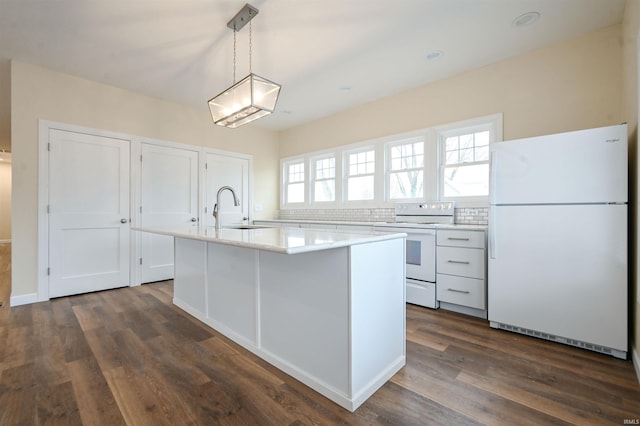 kitchen with sink, white appliances, hanging light fixtures, white cabinets, and a kitchen island