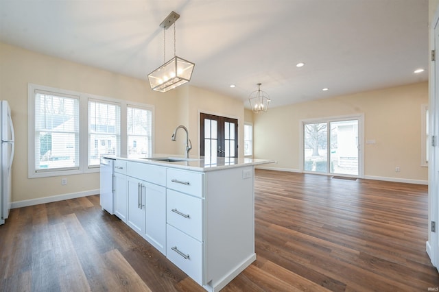 kitchen with a kitchen island with sink, sink, hanging light fixtures, and white cabinets