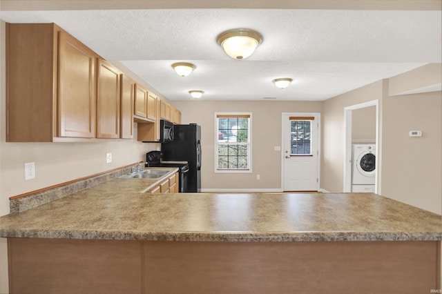 kitchen with black appliances, washer / dryer, sink, kitchen peninsula, and a textured ceiling