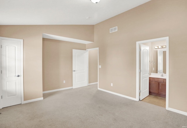 unfurnished bedroom with sink, ensuite bath, light colored carpet, and high vaulted ceiling