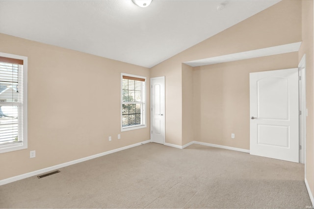 empty room featuring lofted ceiling and light carpet