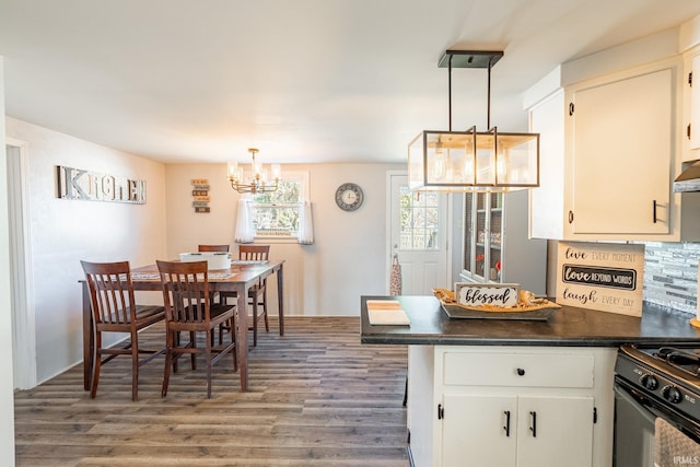 kitchen with tasteful backsplash, wood-type flooring, white cabinets, hanging light fixtures, and gas stove