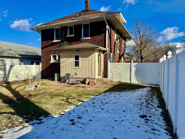 snow covered back of property with a yard