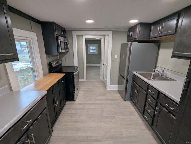 kitchen with stainless steel appliances, sink, and light hardwood / wood-style flooring