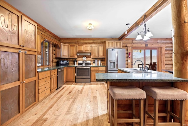 kitchen with pendant lighting, sink, a breakfast bar, rustic walls, and stainless steel appliances