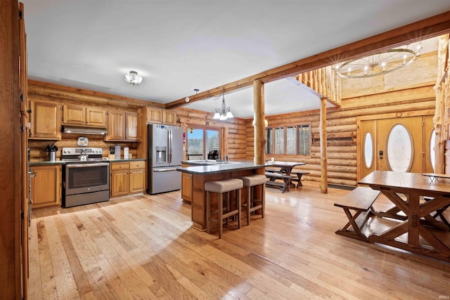 kitchen with a kitchen island, appliances with stainless steel finishes, a breakfast bar, light hardwood / wood-style floors, and beam ceiling