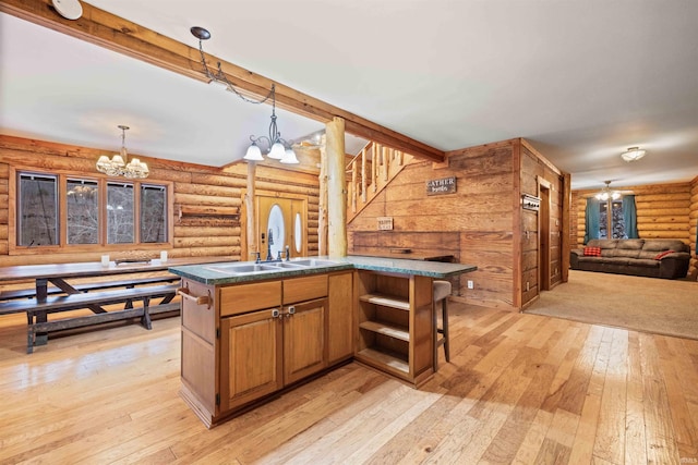 kitchen featuring an island with sink, a chandelier, sink, and a breakfast bar area