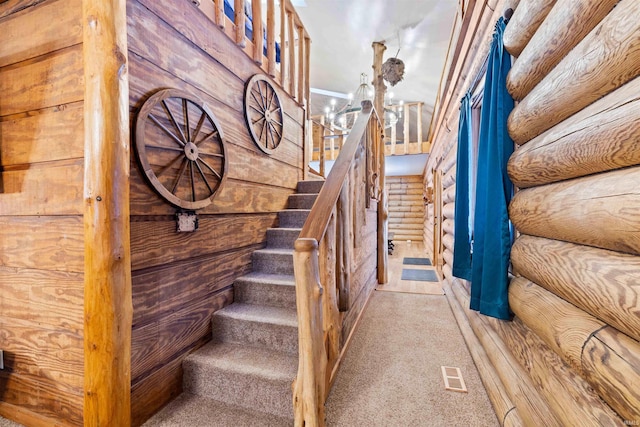 staircase with log walls, carpet, and a notable chandelier