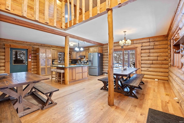 dining room with light hardwood / wood-style flooring, a high ceiling, a notable chandelier, log walls, and beamed ceiling