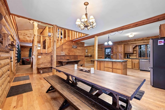 dining area featuring beamed ceiling, sink, a chandelier, and light wood-type flooring