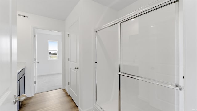 bathroom with a stall shower, visible vents, wood finished floors, and vanity