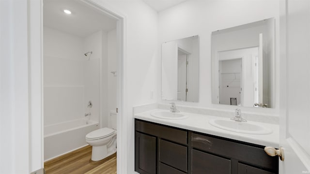 full bathroom featuring double vanity, wood finished floors, toilet, and a sink