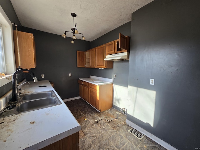 kitchen featuring decorative light fixtures, sink, a textured ceiling, and a notable chandelier