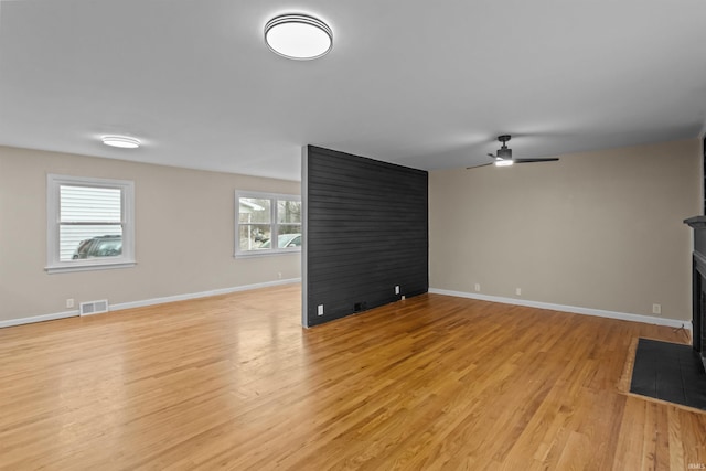 unfurnished living room with light hardwood / wood-style flooring, ceiling fan, and a multi sided fireplace