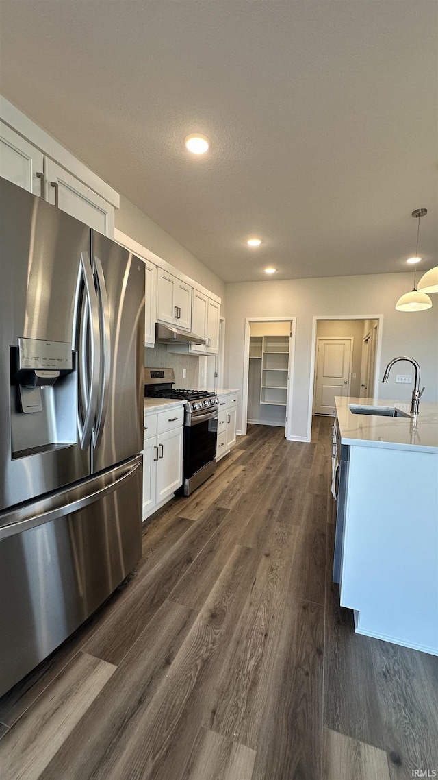 kitchen featuring dark wood-style flooring, a sink, stainless steel appliances, light countertops, and white cabinets