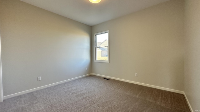 unfurnished room featuring dark colored carpet, visible vents, baseboards, and vaulted ceiling