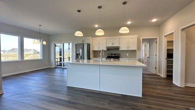 kitchen featuring a sink, dark wood-style floors, appliances with stainless steel finishes, light countertops, and decorative backsplash