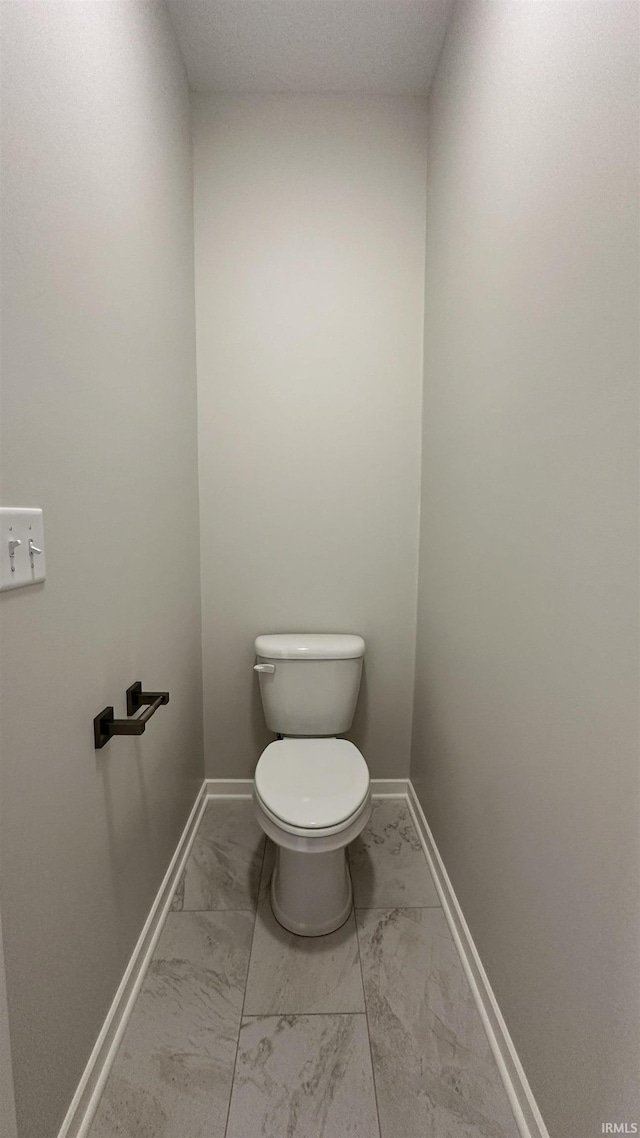 bathroom featuring marble finish floor, toilet, and baseboards