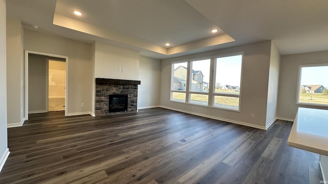 unfurnished living room featuring a wealth of natural light, a raised ceiling, and dark wood-type flooring