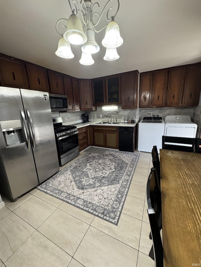 kitchen with sink, light tile patterned floors, appliances with stainless steel finishes, pendant lighting, and washer and clothes dryer