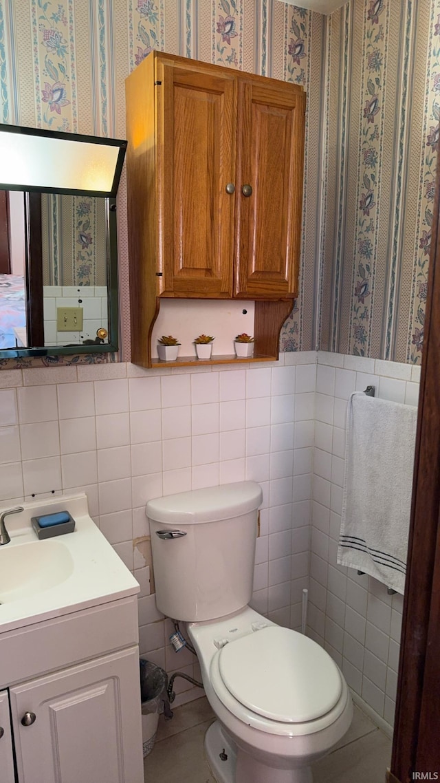 bathroom featuring vanity, toilet, and tile walls