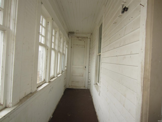 hallway featuring wood ceiling and wood walls