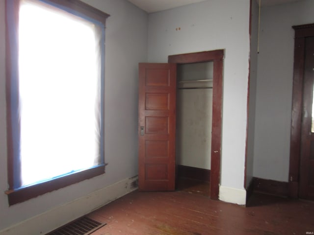 unfurnished bedroom with dark wood-type flooring and a closet