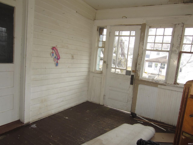 doorway with wooden walls and dark hardwood / wood-style flooring