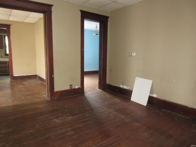 spare room featuring a drop ceiling and dark wood-type flooring