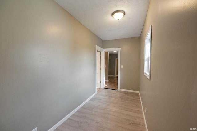 hallway with light hardwood / wood-style floors and a textured ceiling