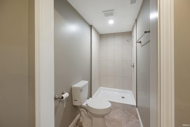 bathroom with tiled shower and toilet