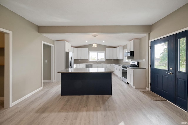 kitchen featuring vaulted ceiling, appliances with stainless steel finishes, pendant lighting, white cabinets, and a center island