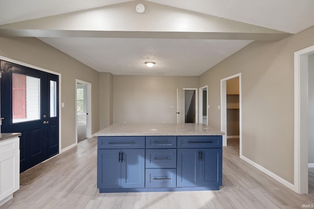 kitchen with lofted ceiling, light stone countertops, and light hardwood / wood-style flooring