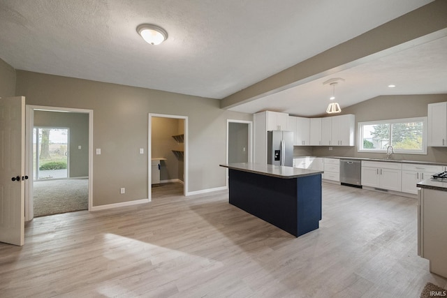 kitchen with pendant lighting, white cabinetry, appliances with stainless steel finishes, and a center island