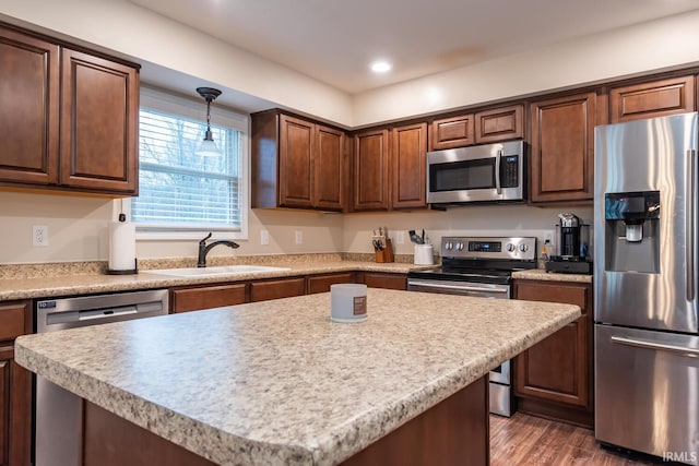 kitchen featuring sink, dark hardwood / wood-style flooring, a kitchen island, pendant lighting, and stainless steel appliances