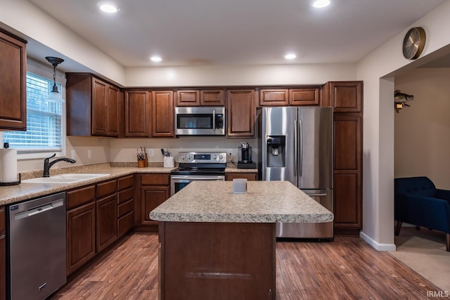 kitchen featuring sink, stainless steel appliances, a center island, dark hardwood / wood-style flooring, and decorative light fixtures