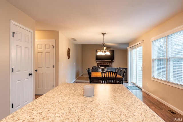 dining room with dark hardwood / wood-style floors and a brick fireplace