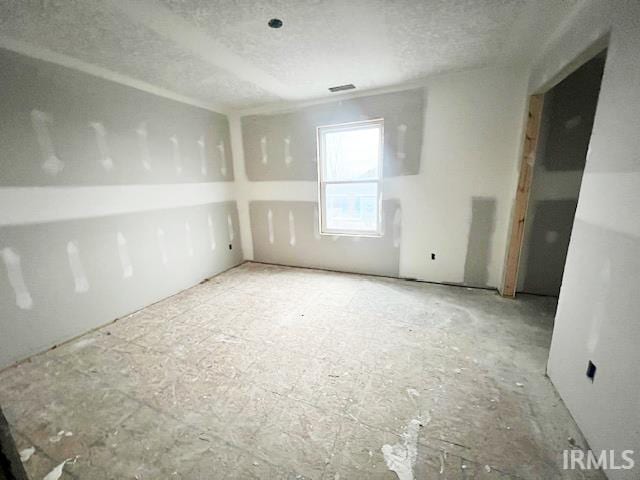 unfurnished room with a textured ceiling