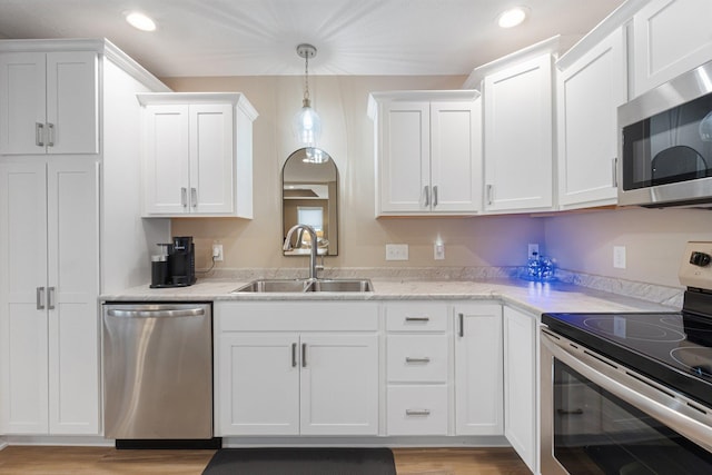 kitchen with sink, white cabinetry, light hardwood / wood-style flooring, pendant lighting, and stainless steel appliances