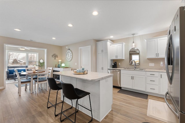 kitchen featuring sink, white cabinets, hanging light fixtures, a center island, and stainless steel appliances