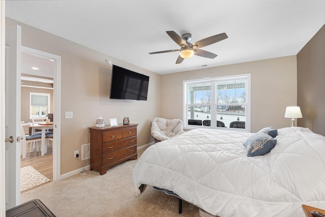 carpeted bedroom featuring ceiling fan and a textured ceiling