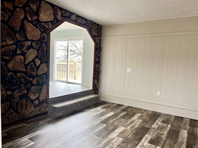 empty room with a textured ceiling and dark hardwood / wood-style flooring