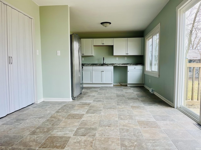 kitchen featuring stainless steel fridge, sink, and white cabinets