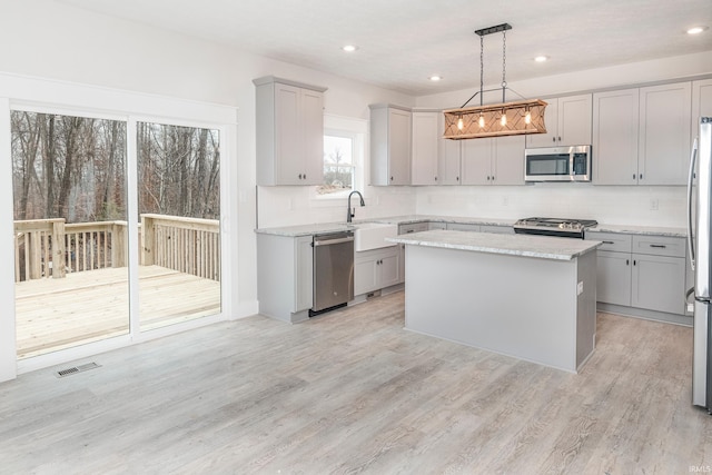 kitchen featuring visible vents, appliances with stainless steel finishes, a center island, gray cabinets, and light wood-style floors