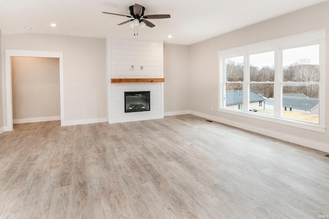 unfurnished living room with a large fireplace, baseboards, light wood finished floors, and recessed lighting