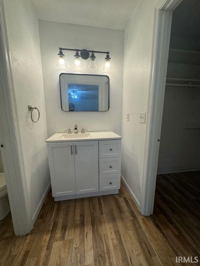 bathroom with wood-type flooring, toilet, and vanity