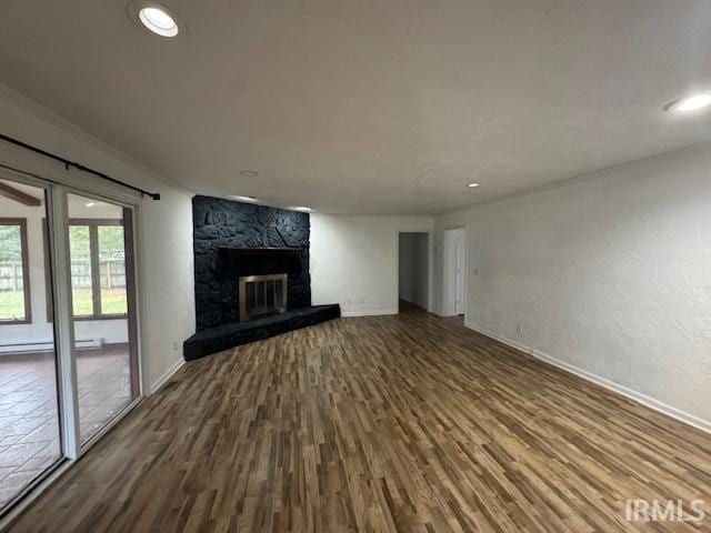 unfurnished living room featuring hardwood / wood-style flooring and a stone fireplace