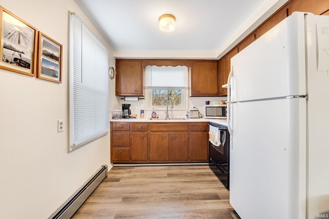 kitchen with electric range oven, sink, white refrigerator, baseboard heating, and light wood-type flooring